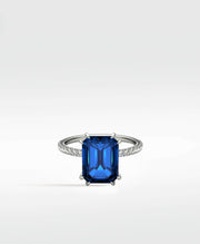 The Flora Azul Engagement Ring, featuring a large emerald-cut blue gemstone and a pavé diamond band in a platinum setting.